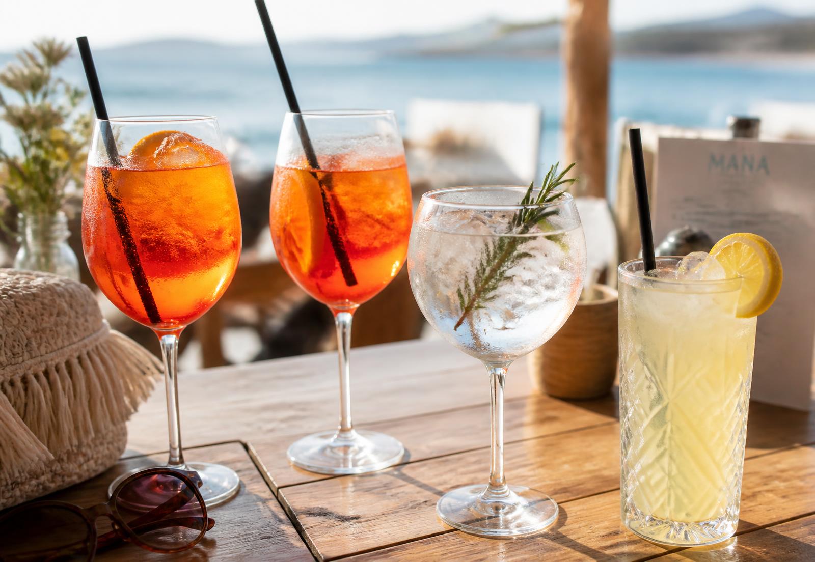Spritz, gin-tonic en verse limonade op een houten tafel op het terras met zee op de achtergrond